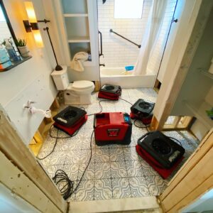 Bathroom flooded with water and lined with drying fans and equipment