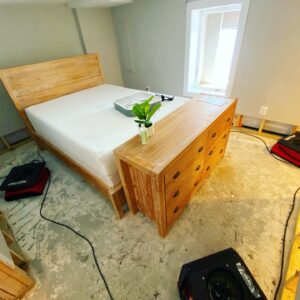 Bedroom with exposed flooring and drying equipment after water damage