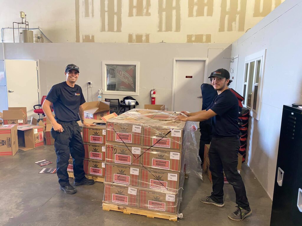 Two technicians preparing equipment on a pallet in the restoration company's warehouse