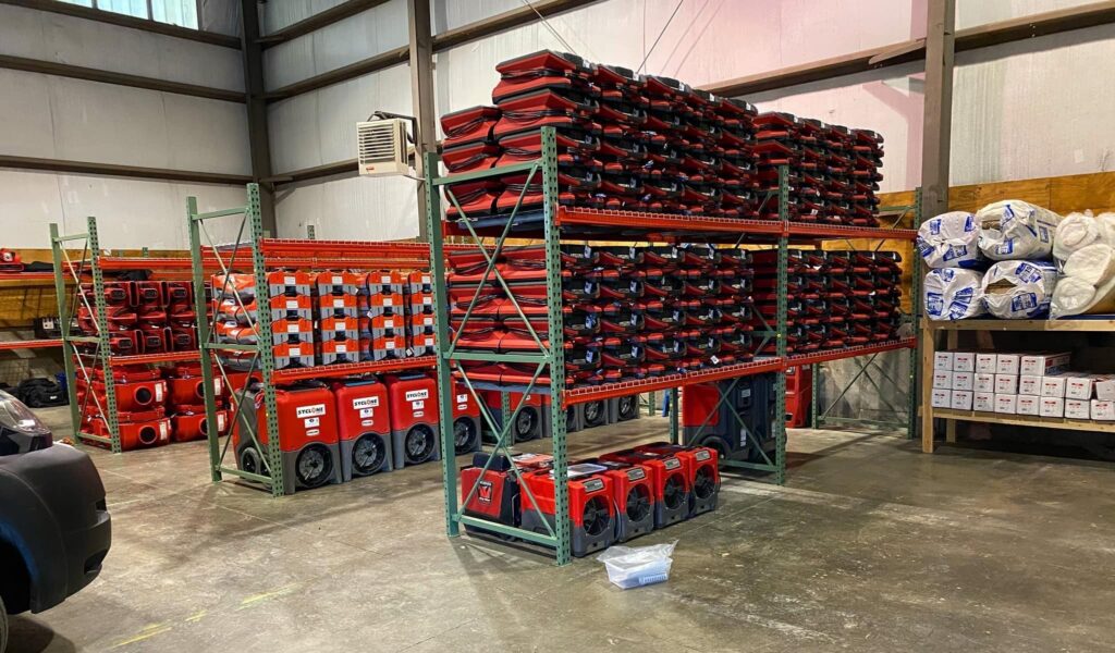 Warehouse racks filled with red air movers and restoration equipment