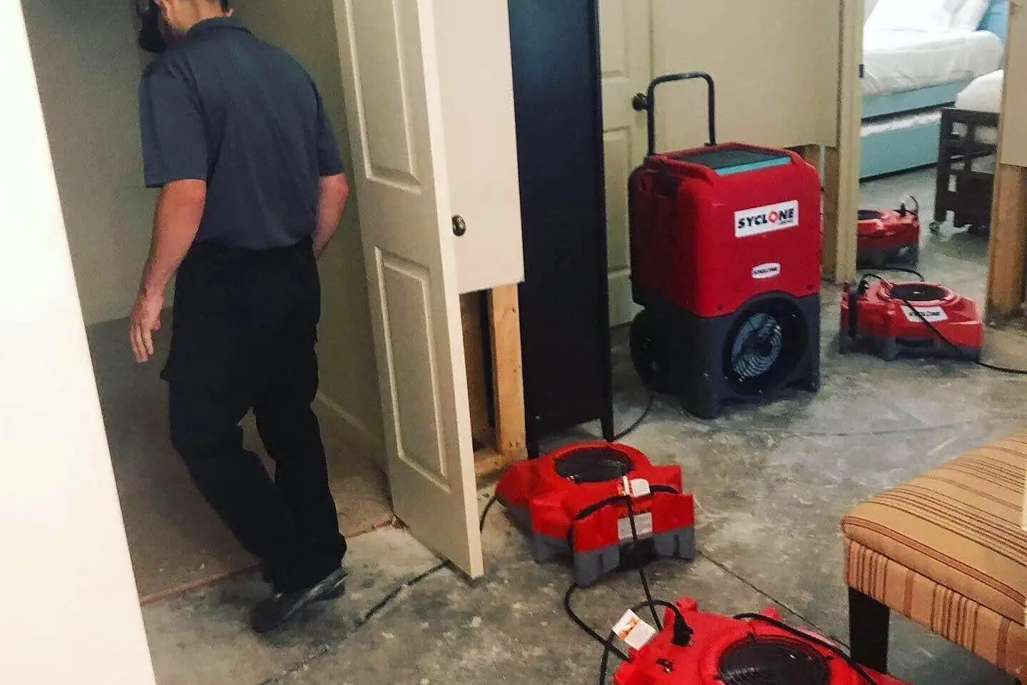 Semper Dry technician checking air movers and a dehumidifier drying a water-damaged room